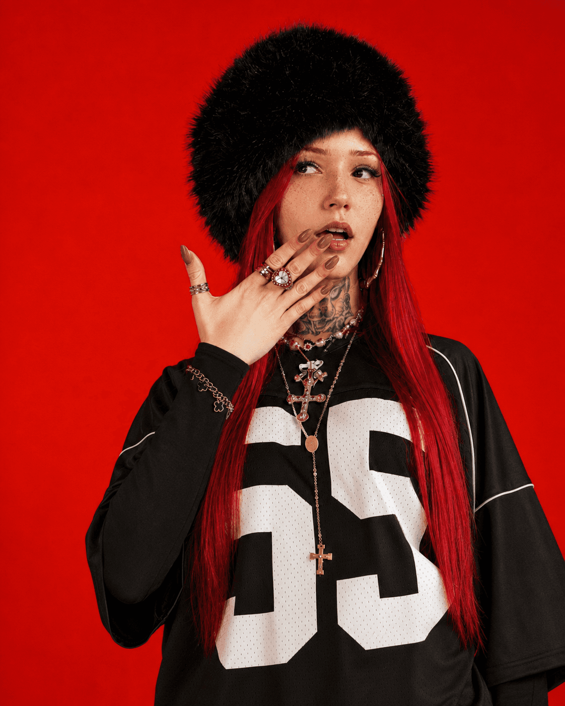 Jenny usando chapéu preto e roupa esportiva sobre fundo vermelho